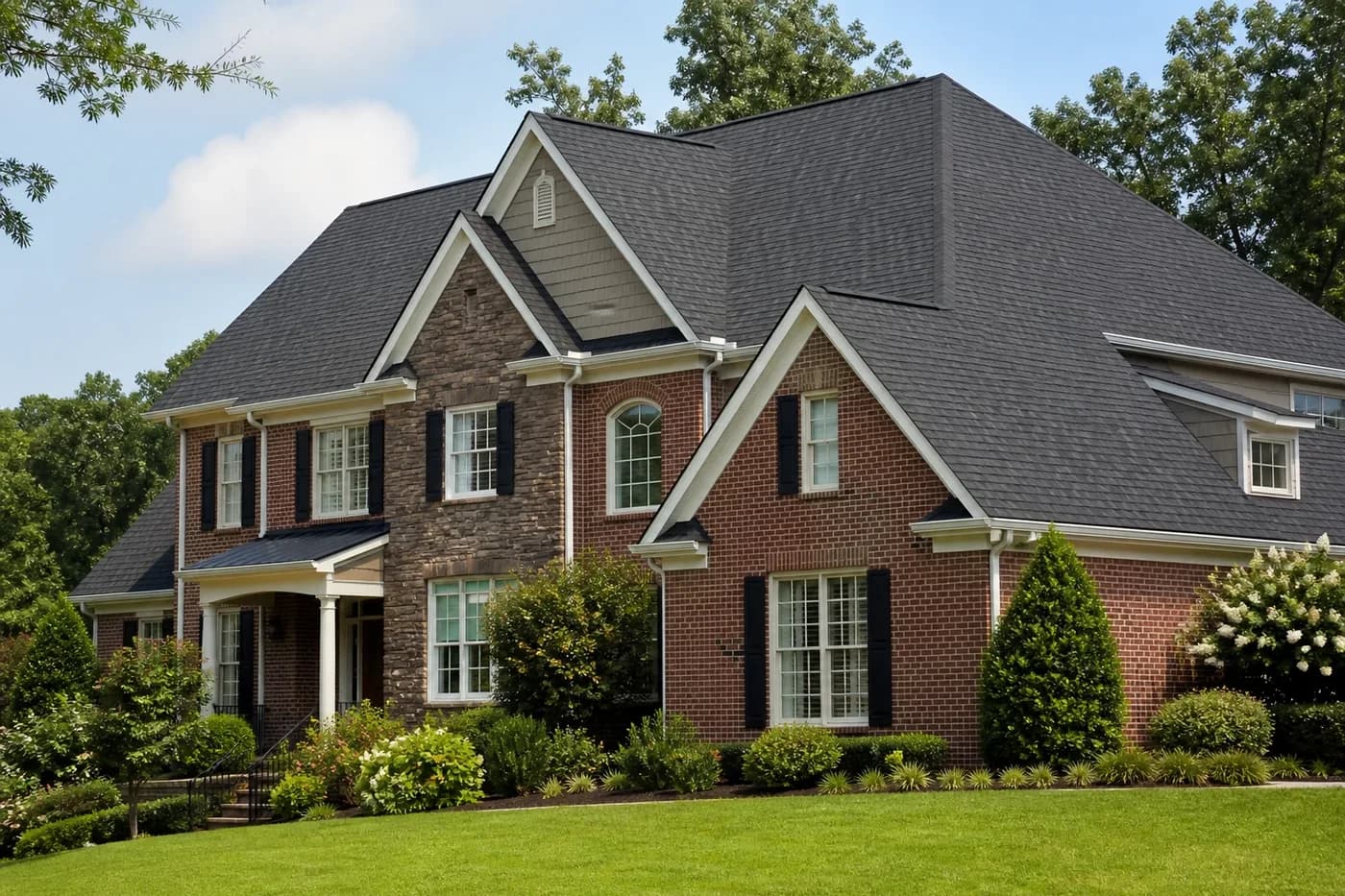 Roof-dominant upscale Indian Trail NC brick-and-stone home with a clean charcoal architectural shingle roof