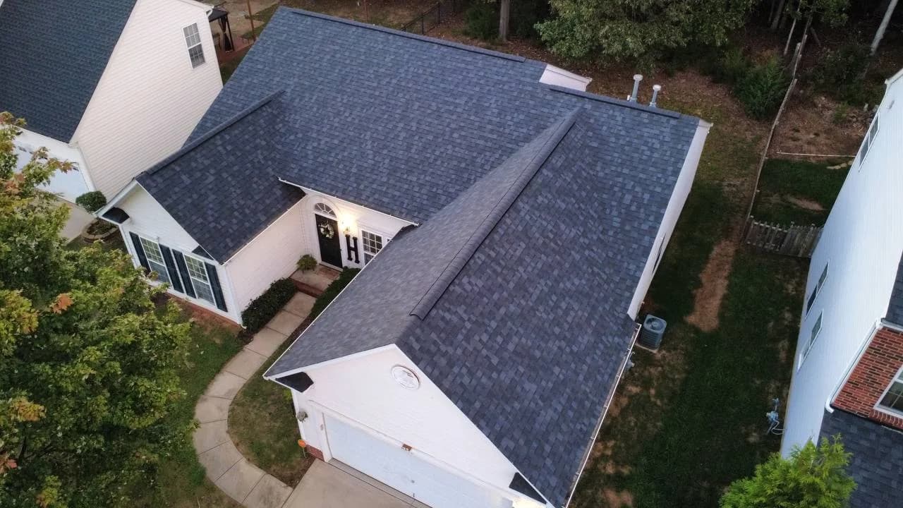 Drone photo of dark architectural shingle roof on a white home by Kaliber Roofing