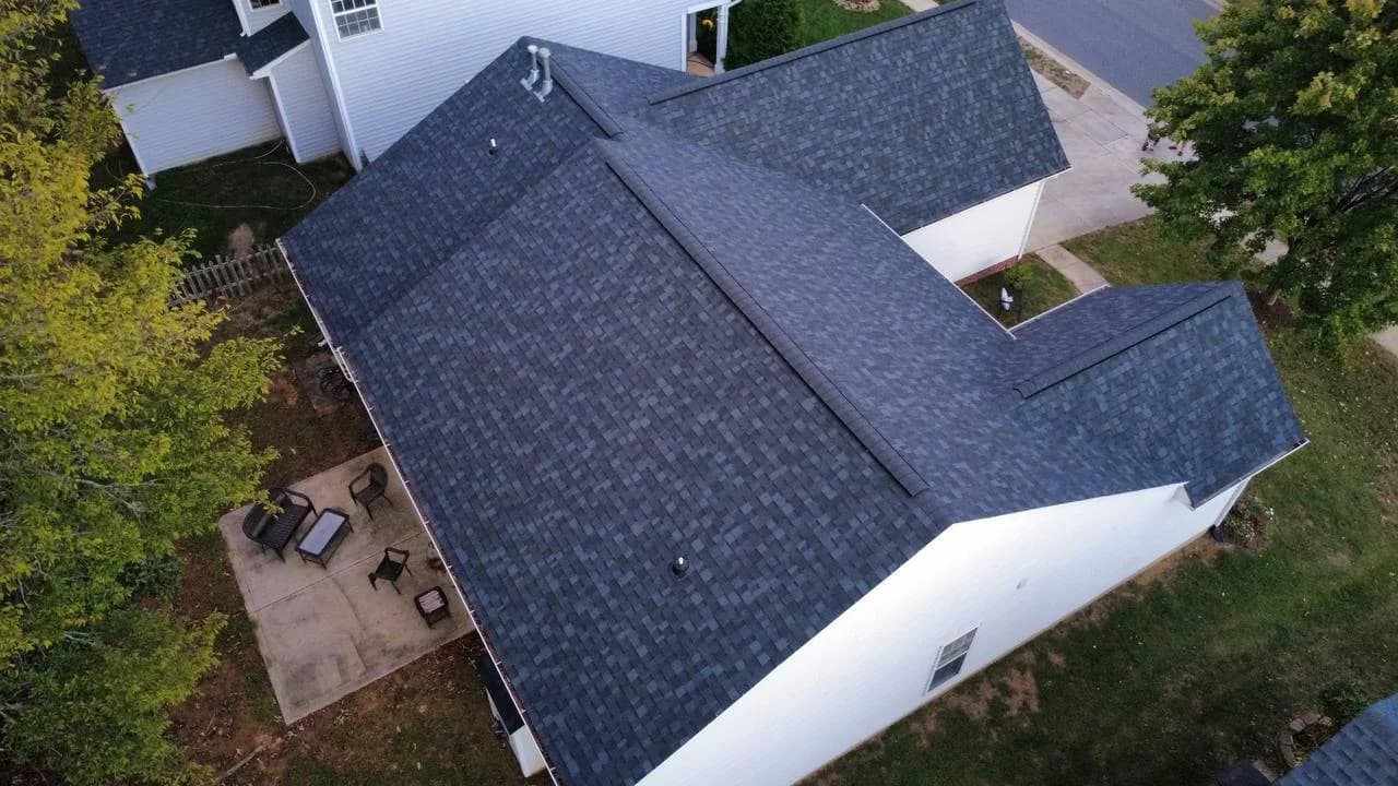 Rear aerial photo of completed asphalt shingle roof on a white residential home