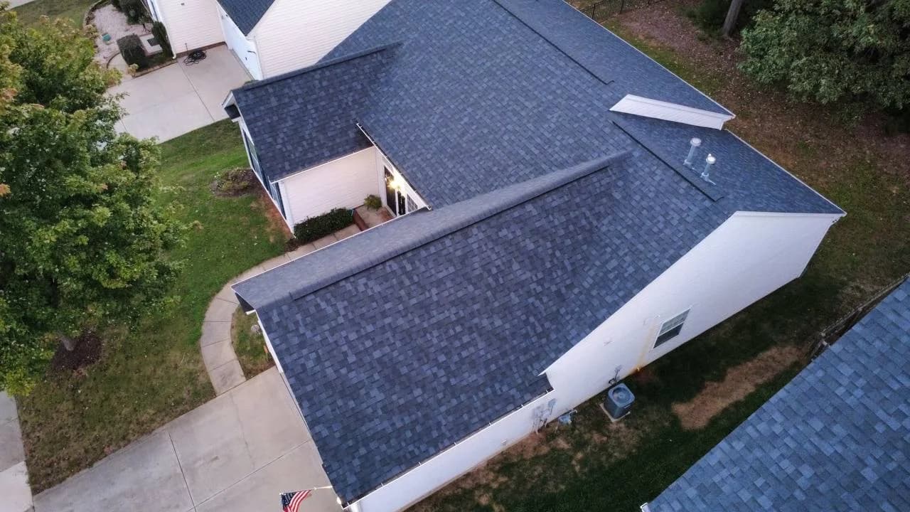 Side drone photo of completed architectural shingle roof on a residential home by Kaliber Roofing