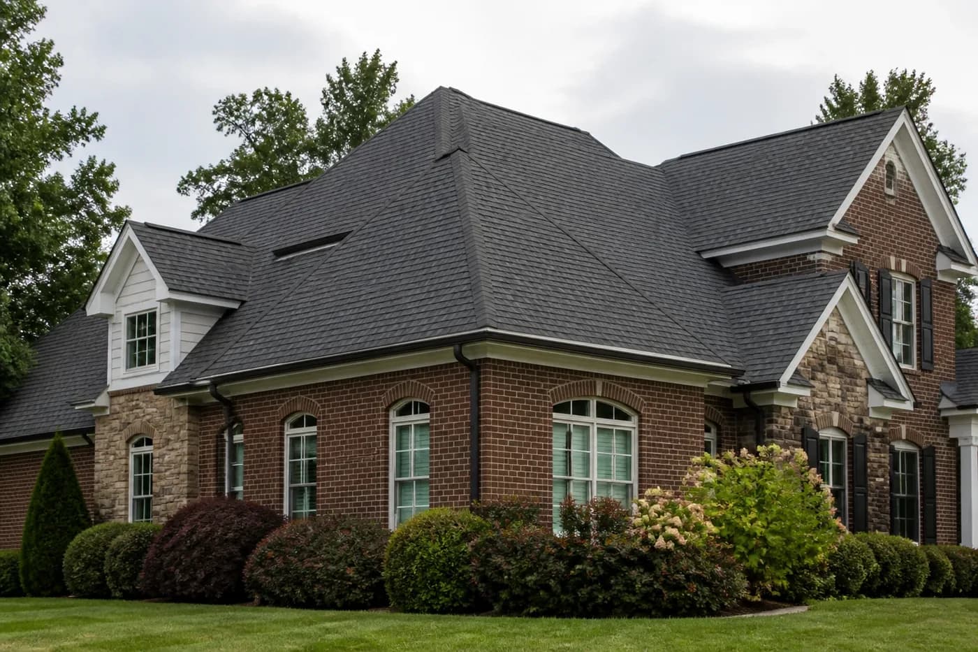 Roof-dominant upscale Indian Trail NC brick home with a clean charcoal architectural shingle roof and tidy landscaping