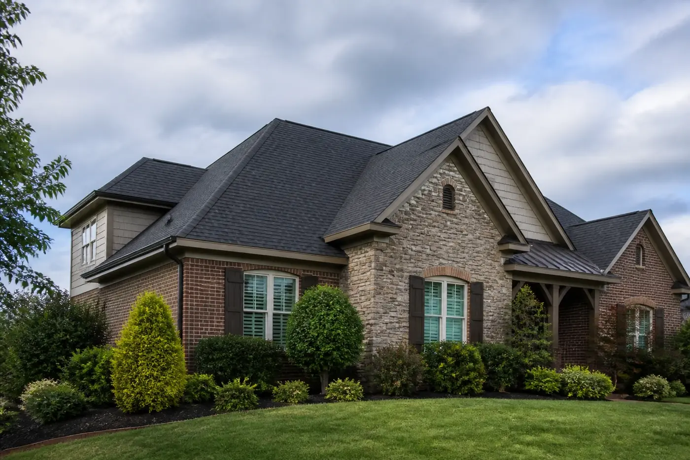 Roof-dominant upscale Indian Trail NC home beneath clearing overcast skies