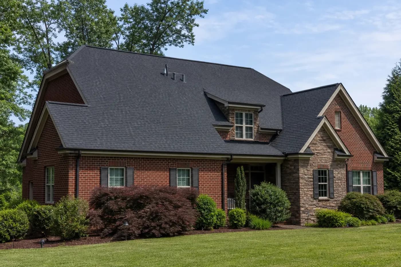 Roof-dominant upscale Indian Trail NC brick home with a broad charcoal architectural shingle roof