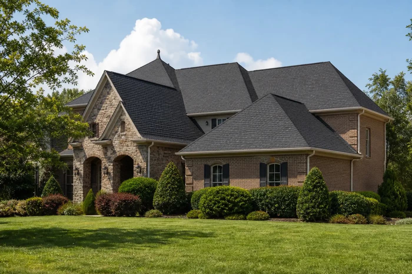 Roof-dominant upscale Indian Trail NC brick-and-stone home with a clean charcoal architectural shingle roof