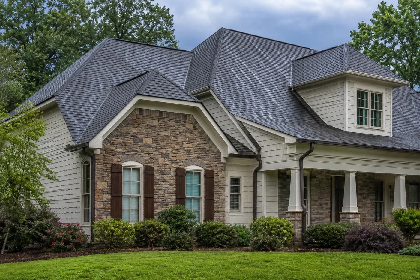 Roof-dominant upscale Wesley Chapel NC home with coherent architectural shingles and roof transitions after light rain