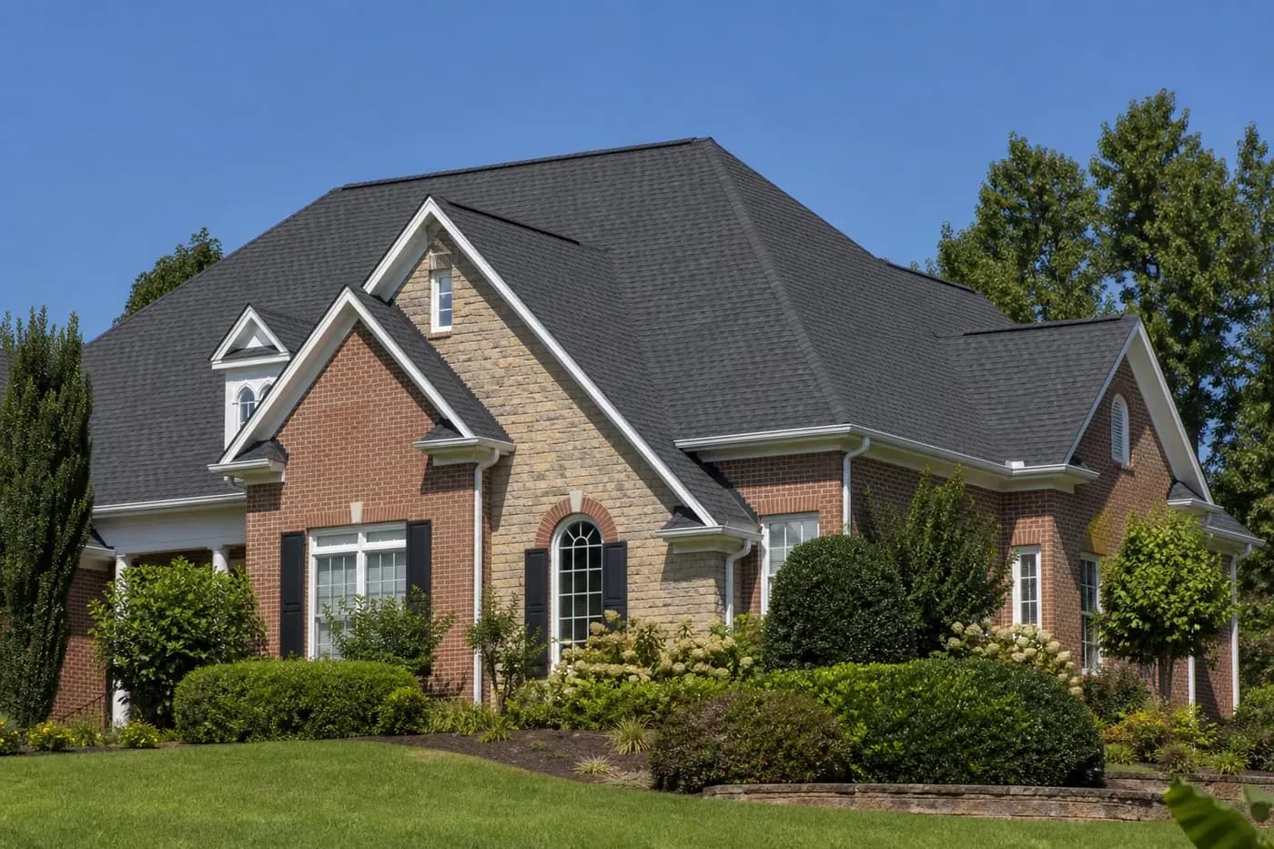 Roof-dominant upscale Indian Trail NC brick home with a clean charcoal architectural shingle roof