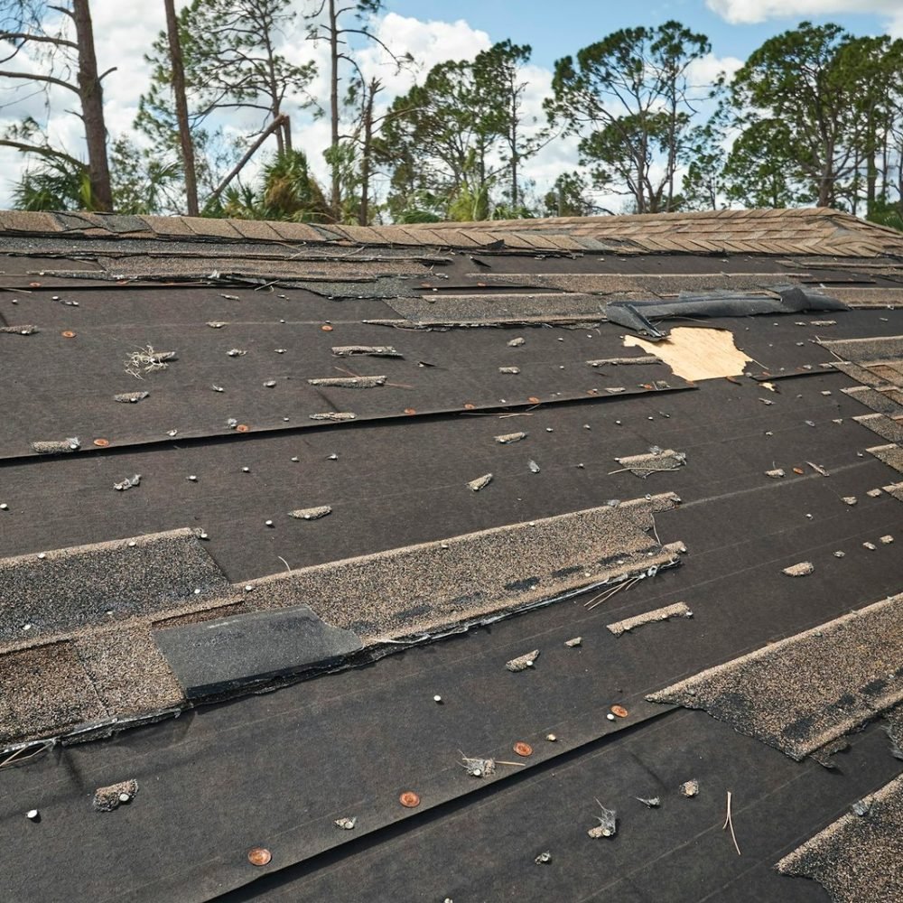 wind-damaged-house-roof-with-missing-asphalt-shingles-after-hurricane-ian-in-florida-.jpg